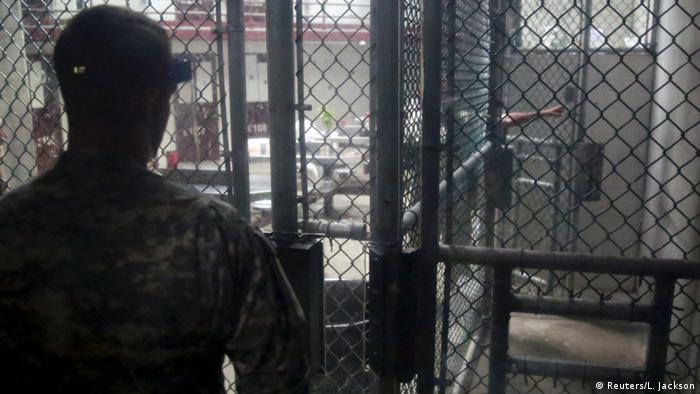 Охранник лагеря Гуантанамо, снятый со спины. Через решетку он наблюдает за происходящим в соседних помещениях