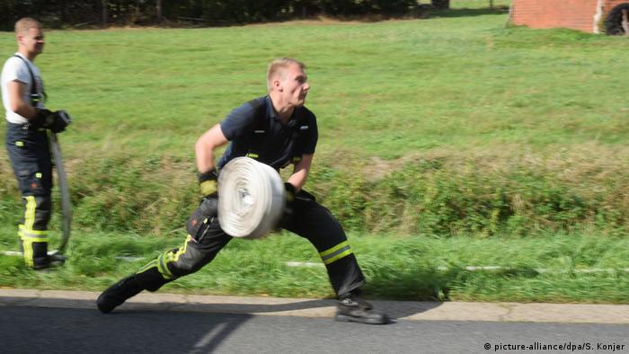 Firefighter rolling out hose (picture-alliance/dpa/S. Konjer)