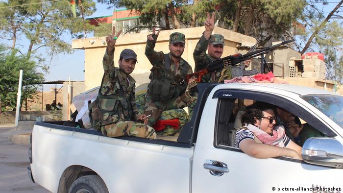 Syrian troops sit in the back of a truck after entering the town of Tall Tamr (picture-alliance/Photoshot)