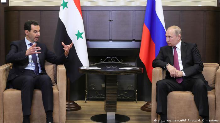 Vladimir Putin and Bashar Assad sit in two chairs in front of their respective flags (picture-alliance/AP Photo/M. Klimentyev)
